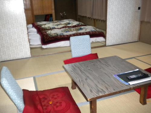 a room with a table and chairs and a bed at Mimatsuso Ryokan in Asahikawa