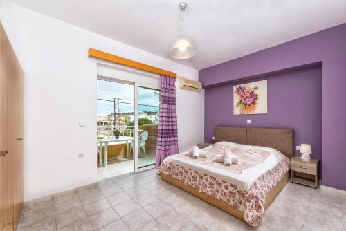 een slaapkamer met een bed met paarse muren en een balkon bij Iliana Apartment in Afantou