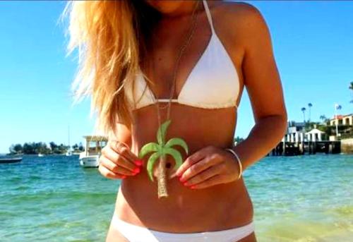 a woman in a white bikini holding a plant at Palmyra Indah Bungalows in Sekotong