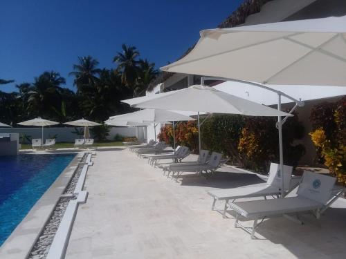 a row of chairs with umbrellas next to a swimming pool at Oasi Encantada - Beach Resort in Santa Cruz de Barahona