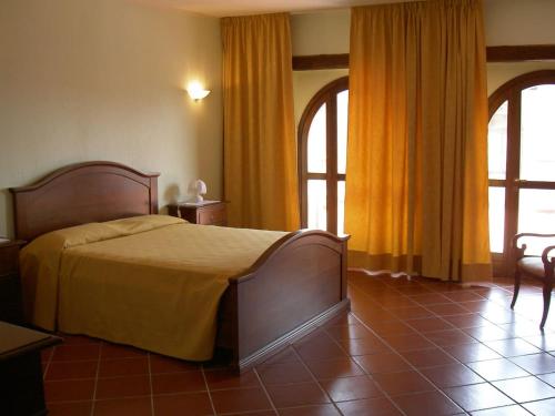 sypialnia z łóżkiem z żółtą pościelą i oknami w obiekcie Bricco di Sant' Eufemia w mieście Bossolasco
