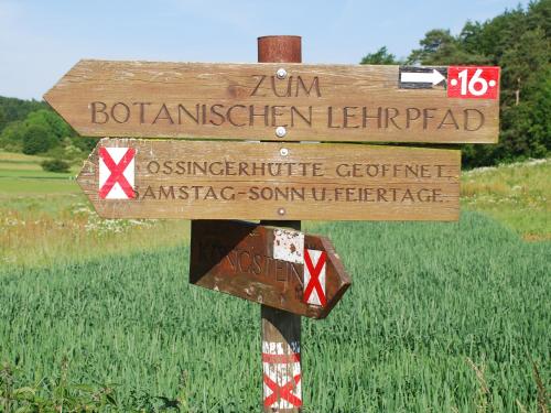 a wooden sign on a pole in front of a field at Hotel Königsteiner Hof in Königstein in der Oberpfalz