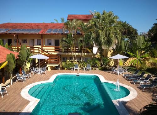 a resort with a pool and chairs and a building at Pousada Camburioca in Camburi