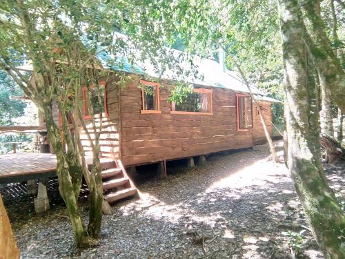a wooden cabin in the woods with a staircase leading to it at Cabaña Rustica Patagonia Chilena in Coñaripe
