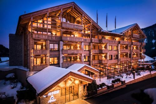 ein großes Holzgebäude im Schnee in der Nacht in der Unterkunft Cocoon - Alpine Boutique Lodge in Maurach