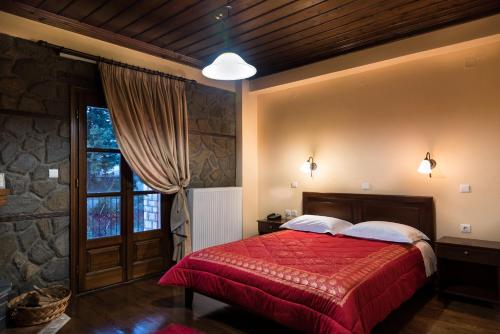 a bedroom with a red bed and a window at Hotel Kroupi in Elati Trikalon