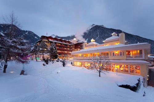 duży budynek w śniegu przed górą w obiekcie Wellnessresidenz Alpenrose w mieście Maurach
