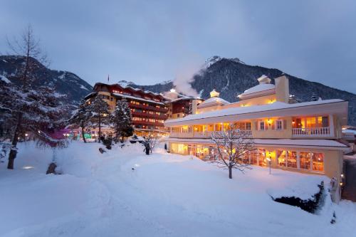 a large building in the snow in front of a mountain at Wellnessresidenz Alpenrose in Maurach