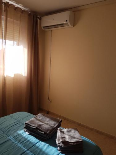 two towels sitting on a bed in a room with a window at Apartamento bahia park 1a linea " Magic world " in Oropesa del Mar