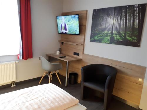 a room with a desk and a tv on the wall at Hotel Bigger Hof - Wirtshaus Platzhirsch am Jahnplatz in Olsberg