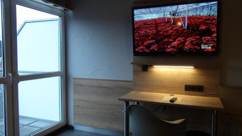a room with a tv on a wall with a table and a window at Hotel Bigger Hof - Wirtshaus Platzhirsch am Jahnplatz in Olsberg