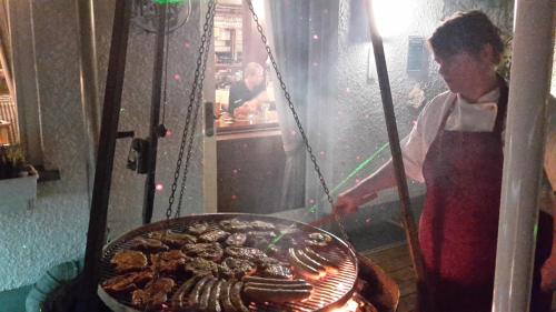 a woman is cooking food on a grill at Hotel Bigger Hof - Wirtshaus Platzhirsch am Jahnplatz in Olsberg