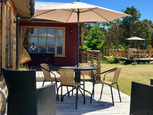 a table and chairs with an umbrella on a deck at El Reflejo Lodge Spa - Queilen - Chiloé in Queilén