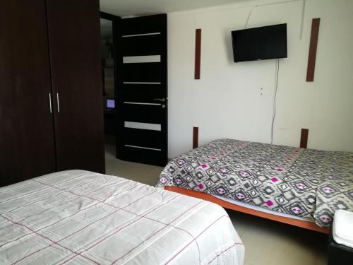 um quarto com uma cama e uma televisão na parede em CASA F'BALUA em Tacna