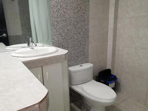 La salle de bains est pourvue de toilettes blanches et d'un lavabo. dans l'établissement CASA F'BALUA, à Tacna