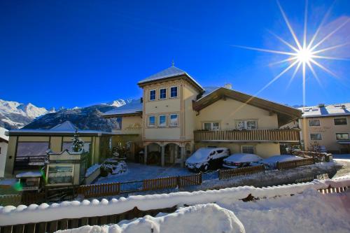 a house in the snow with the sun in the sky at ALPENAPART LADIS ehemals Alpenapart Alexander in Ladis