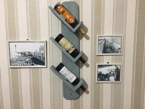 a shelf on a wall with wine bottles and pictures at Old Tiraspol Hostel in Tiraspol