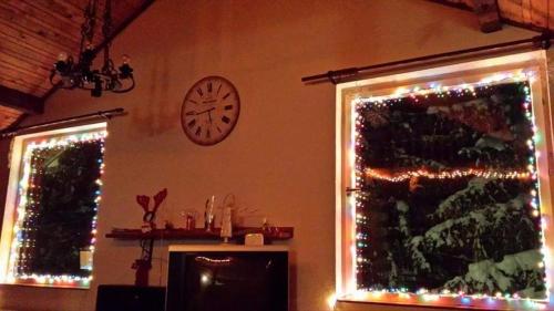 a clock on the wall above two windows with christmas lights at Apartments Cosic in Vlasic