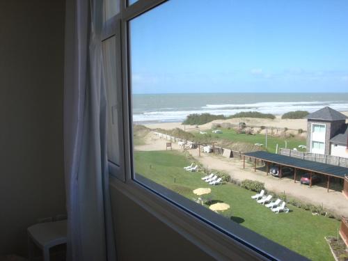 a window with a view of a beach and the ocean at Cariló Sul Mare in Carilo