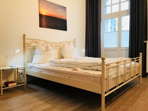 - une chambre dotée d'un grand lit avec des draps et des oreillers blancs dans l'établissement Haus am Park - Wohnung 24, à Kühlungsborn