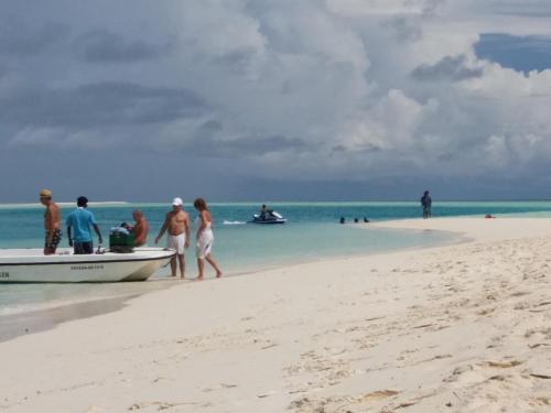 a group of people walking on a beach next to a boat at Ras Rana Lodge in Rasdu