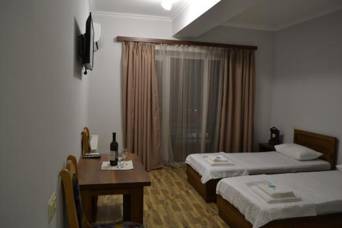 a hotel room with two beds and a table and a window at The Wine Hotel Telavi in Tʼelavi