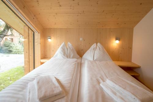 a bed in a wooden room with white sheets and pillows at Aron Chalet Kreischberg 10A in Sankt Lorenzen ob Murau