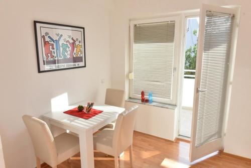 a white dining room with a white table and chairs at Promenada apartmani in Kruševac