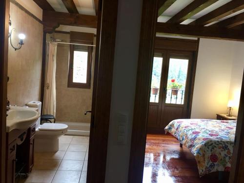 a bedroom with a bed and a bathroom with a sink at La Casuca de Pumareña in Pumareña