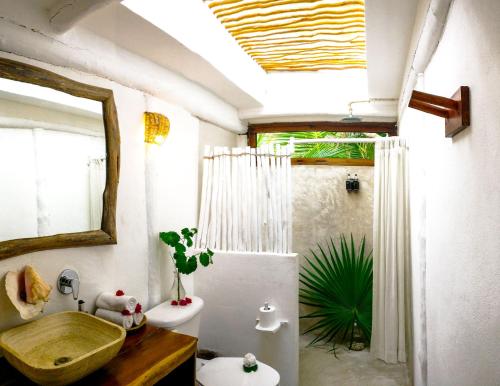 y baño con lavabo, aseo y espejo. en Casa Violeta, en Tulum