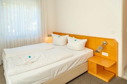 een bed met witte lakens en kussens in een kamer bij Apartment Astra in Zempin