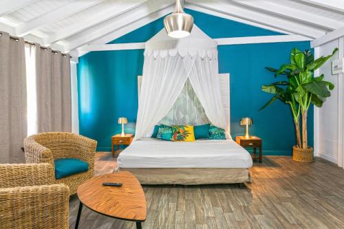 グラン・カーズにあるKoho SXM - ex Hevea Hotelの青い壁のベッドルーム1室、天蓋付きベッド1台が備わります。