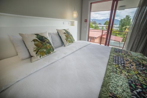 a bedroom with a large white bed with a window at Red Tussock Motel in Te Anau