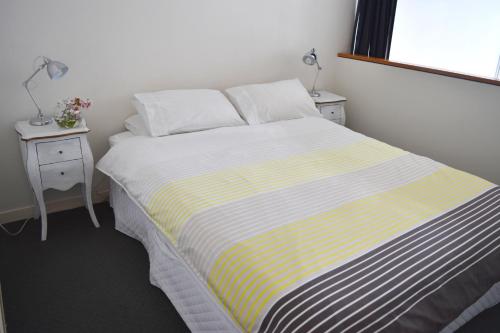 uma cama num quarto com duas mesas de cabeceira e dois candeeiros em Downtown Townhouse Special em Auckland