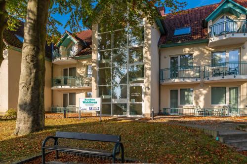 a park bench in front of a building at Apartment Fridolin mit Balkon- nur 200m bis zum Strand in Zempin