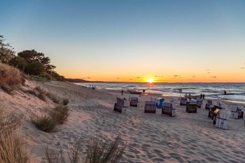 a beach with chairs and the ocean at sunset at Apartment Fridolin mit Balkon- nur 200m bis zum Strand in Zempin