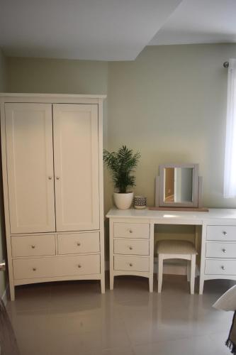 a bedroom with a dresser and a desk with a mirror at The Spinney in Bracknell
