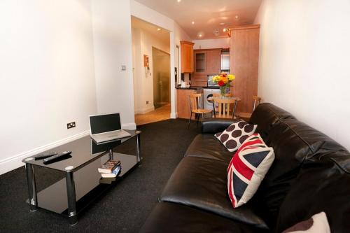a living room with a couch and a table with a laptop at Lace Market Apartments - City Centre - 4 Beds Apartment with 2 Bathrooms and full Kitchen in George Street - close to Victoria Centre Shopping Centre and the Mercure Hotel - Outdoor Parking for Cars or Vans at five pounds a day in Nottingham