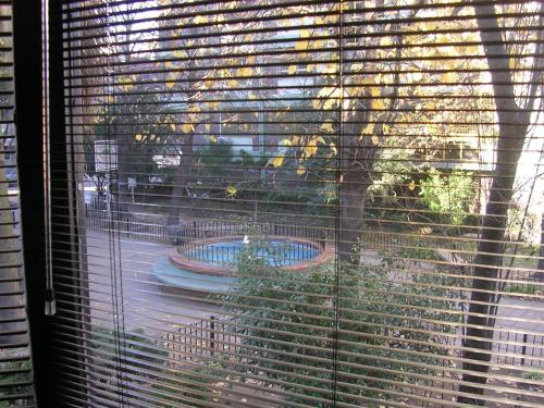 uma janela com persianas com vista para um quintal em Premium Loft of the Fountain Small Plaza w/Netflix em Buenos Aires