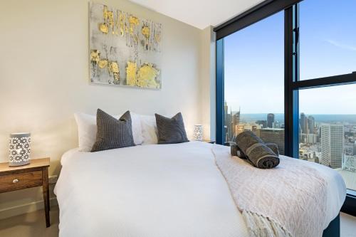 a bedroom with a white bed and a large window at Studio# on Collins in Melbourne