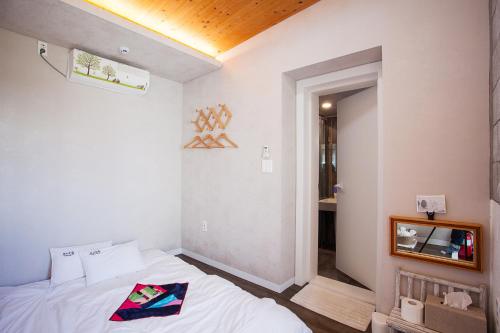 1 dormitorio con 1 cama y 1 habitación con pasillo en Bookmark Guesthouse, en Seogwipo