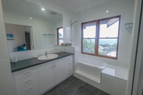 a white bathroom with a sink and a window at Absolute Airlie in Airlie Beach