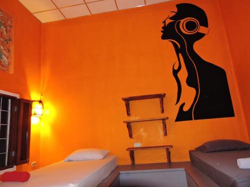 a room with two beds and a painting of a woman at Buena Onda Backpackers in San Juan del Sur