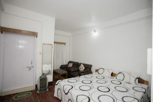 a bedroom with a bed and a couch and a chair at Bliss Homestay in Tawang
