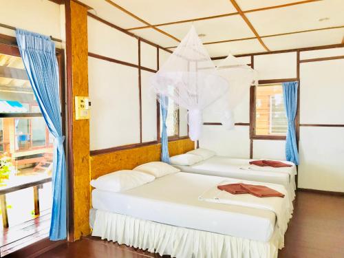 Libong Beach Resort في ليبونغ: سريرين في غرفة مع ستائر زرقاء