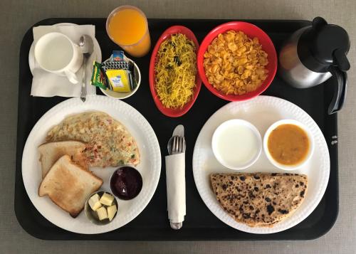 ein Tablett mit Speisen, darauf Teller mit Essen. in der Unterkunft STAAYZ Premium Gurgaon in Gurgaon