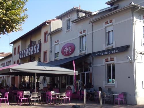 un bâtiment avec des tables et des chaises devant lui dans l'établissement Hôtel du Centre, à Soustons