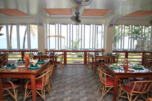 a restaurant with wooden tables and chairs and windows at Badladz Beach and Dive Resort in Puerto Galera