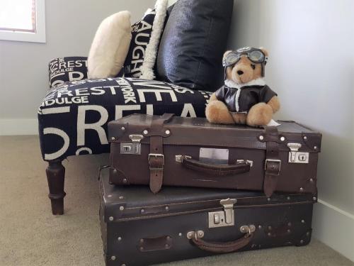 a teddy bear sitting on top of two suitcases at Villa Te Soro Bed and breakfast in Auckland