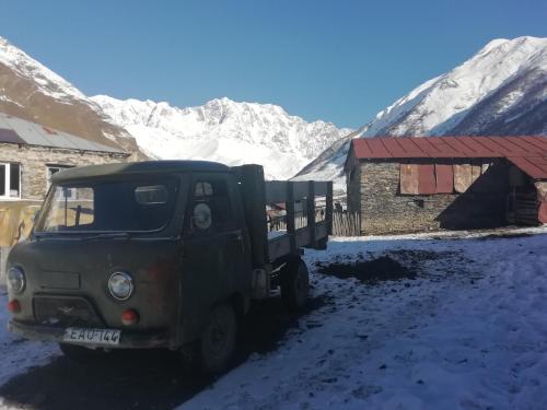 a green truck parked in front of a snow covered mountain at Guesthouse Angelina in Ushguli